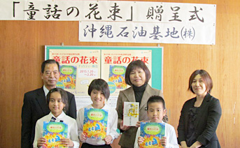 「童話の花束」を手に喜ぶ児童と同社総務部部長（左）